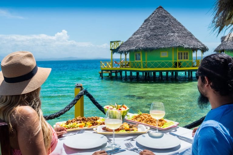 Couple having lunch on a deck facing an overwater palafito