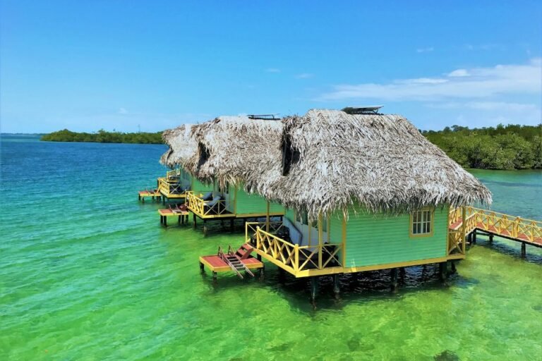 Overwater palafitos on clear green water with mangroves behind