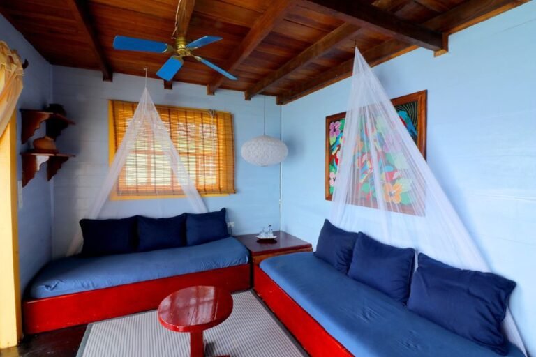 Palafito bedroom with sofa beds, a mosquito net and a ceiling fan
