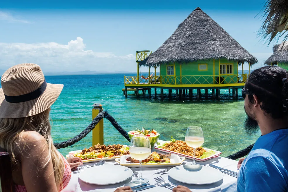 Couple having lunch on a deck facing an overwater palafito