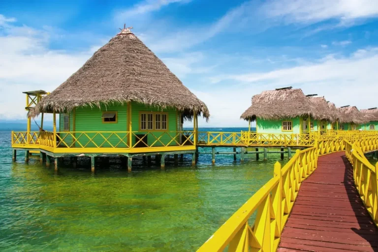 Two-storey palafito with palm roof next to the yellow walkway