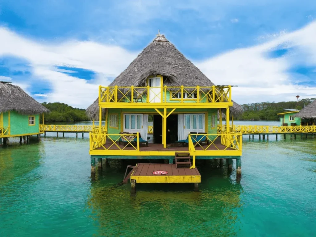 Two-story overwater palafito with yellow railings and a deck at sea level